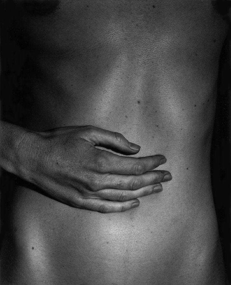 Black and white photo showing a closeup of a hand on a naked belly