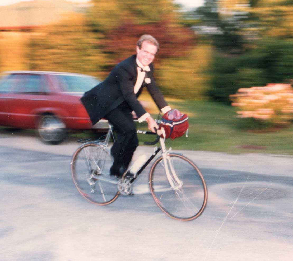 Philip Shepherd wearing a tuxedo and riding his bicycle 