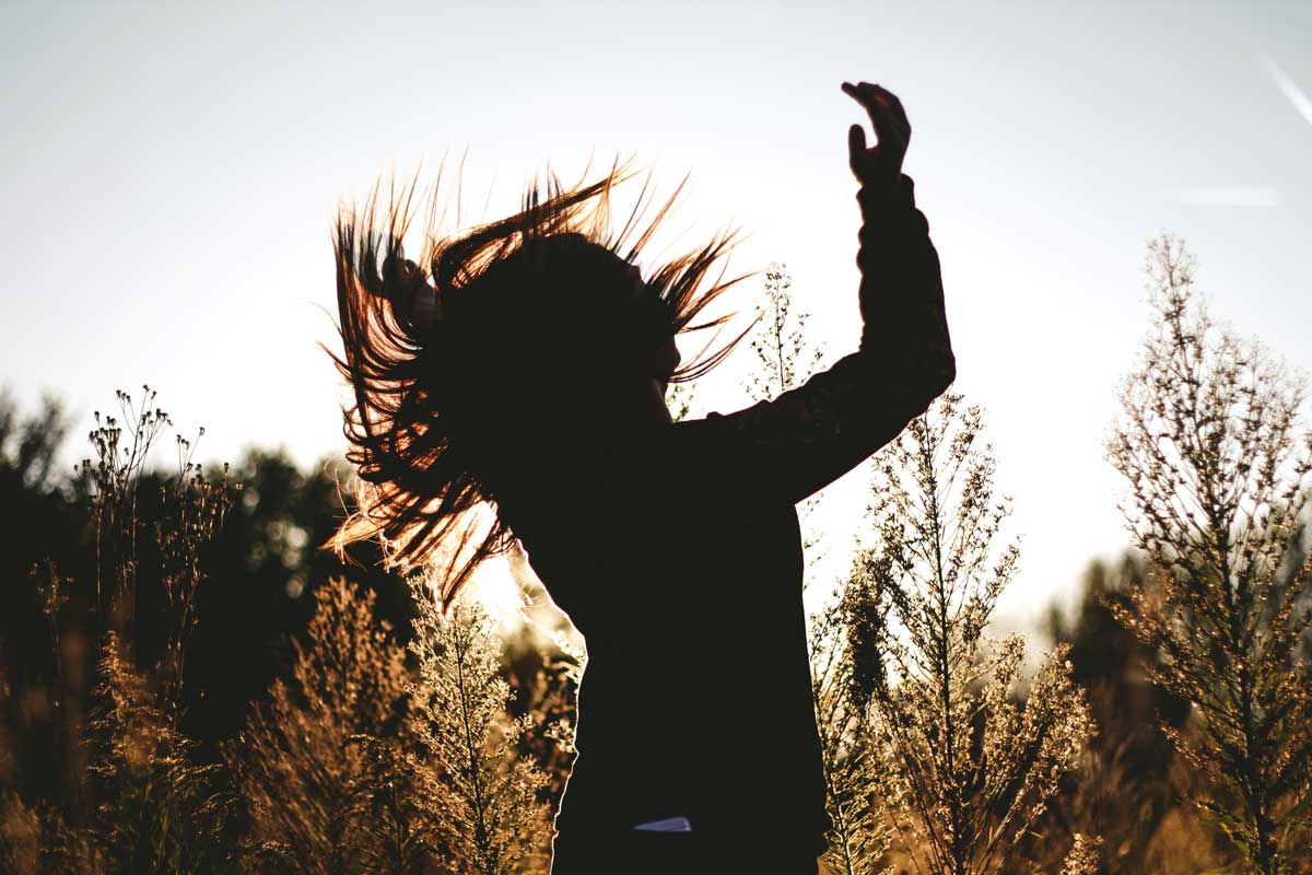 silhouette of person dancing in grasses
